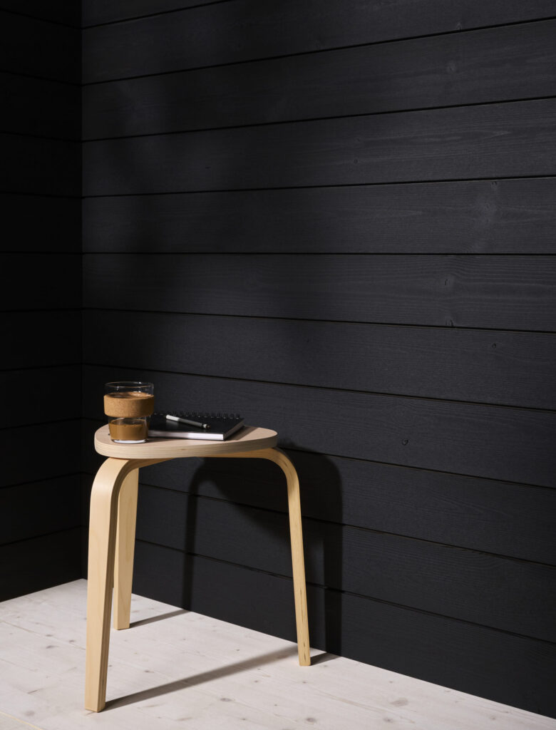 Musta puupaneeliseinä ja puinen jakkara